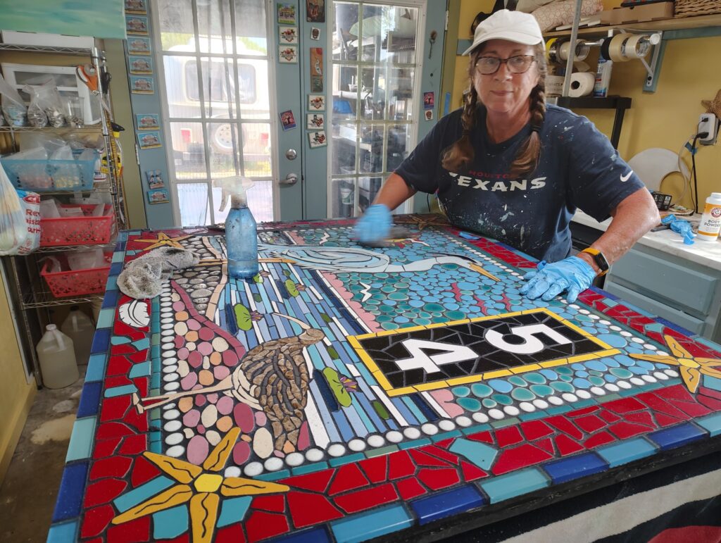 An artist works on a colorful mosaic table
